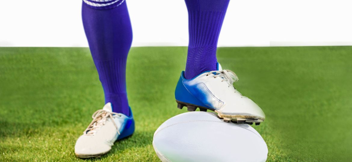 Rugby player posing feet on the ball